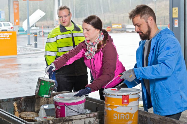 Sortti-aseman asiakkaat laittavat maalipurkkeja vaarallisen jätteen keräykseen.