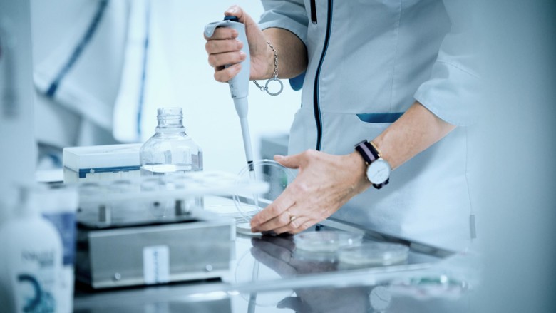 Laboratoriotyöntekijä pipetoi petrimaljalle.